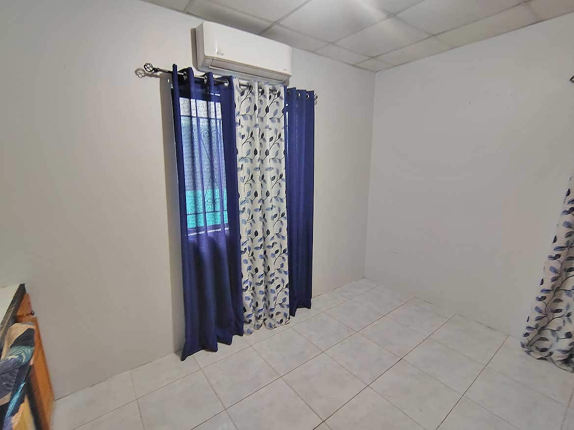 Cornerstone™ Cashew Gardens Room Cornerstone- Room with air conditioning and blue curtains at Cornerstone™.
