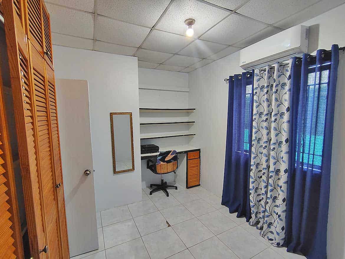 Interior of Cashew Gardens, Edinburgh Cornerstone- Room with white walls, blue curtains, and a small desk with shelves.