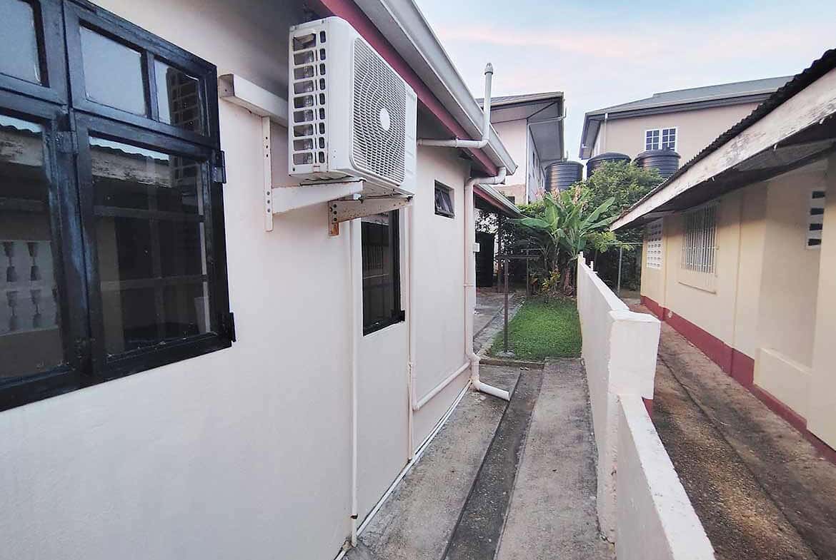 Cornerstone- Exterior view of a 3-bedroom home in Dinsley Gardens with air conditioning unit.