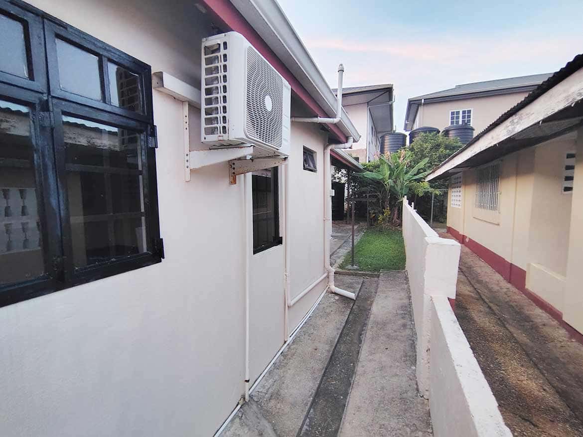 Dinsley Gardens 3-Bedroom Home Exterior Cornerstone- Exterior view of a 3-bedroom home in Dinsley Gardens with air conditioning unit.