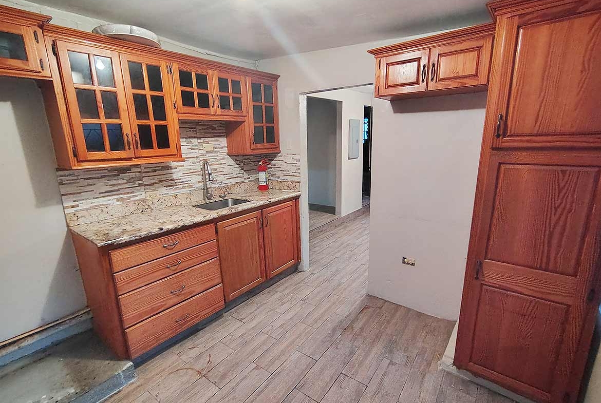 Cornerstone- Spacious kitchen with wooden cabinets and granite countertops in Dinsley Gdns home.