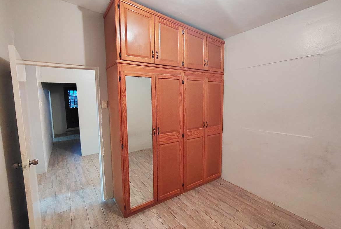 Cornerstone- Spacious bedroom with built-in wooden wardrobe and mirror.
