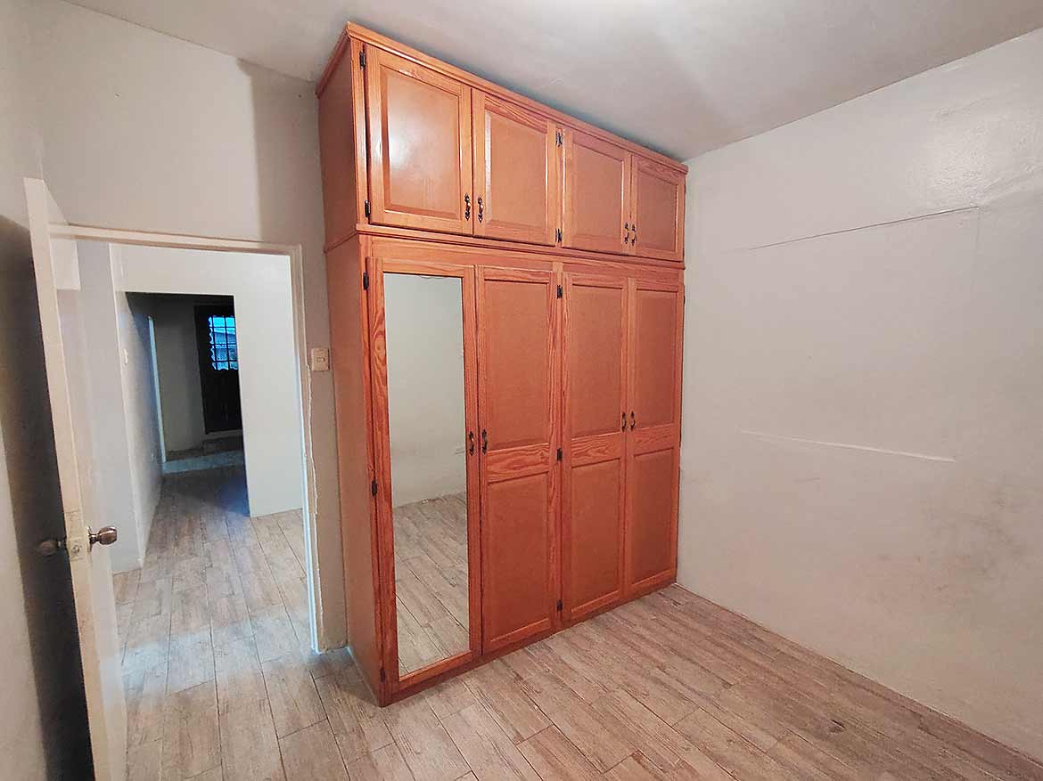 Built-in Wooden Wardrobe in Bedroom Cornerstone- Spacious bedroom with built-in wooden wardrobe and mirror.