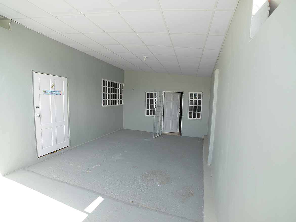 Apartment Building Interior at Five Rivers Cornerstone- Empty apartment corridor with white walls and multiple windows at Five Rivers.