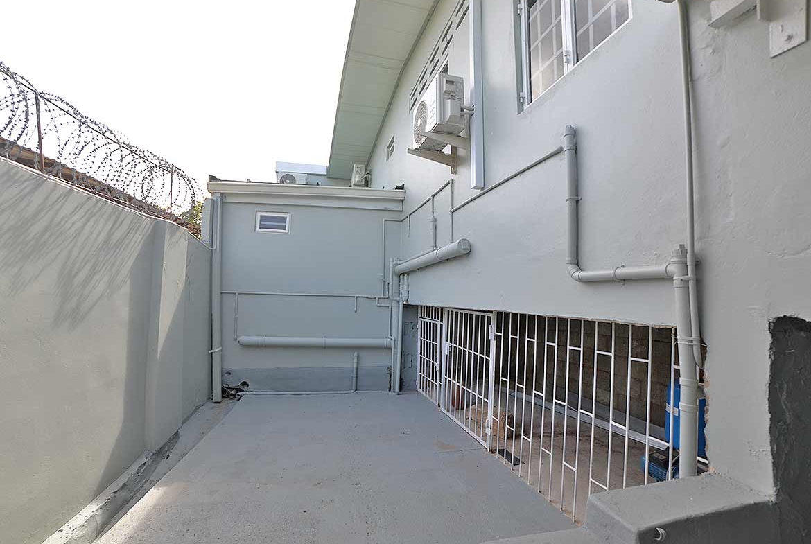 Cornerstone- Exterior view of Cornerstone™ apartment building with security fencing and air conditioning units.
