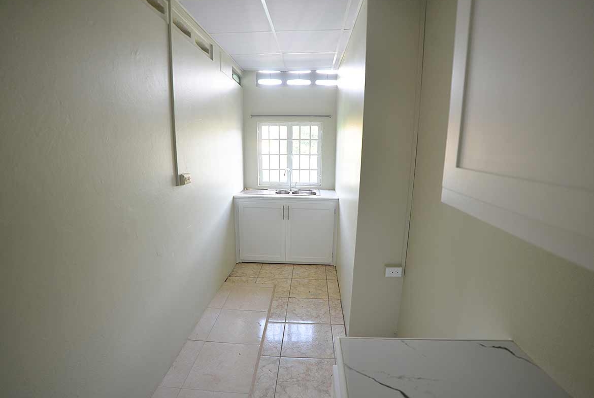 Cornerstone- Bright kitchen with window and white cabinets in Five Rivers apartment.
