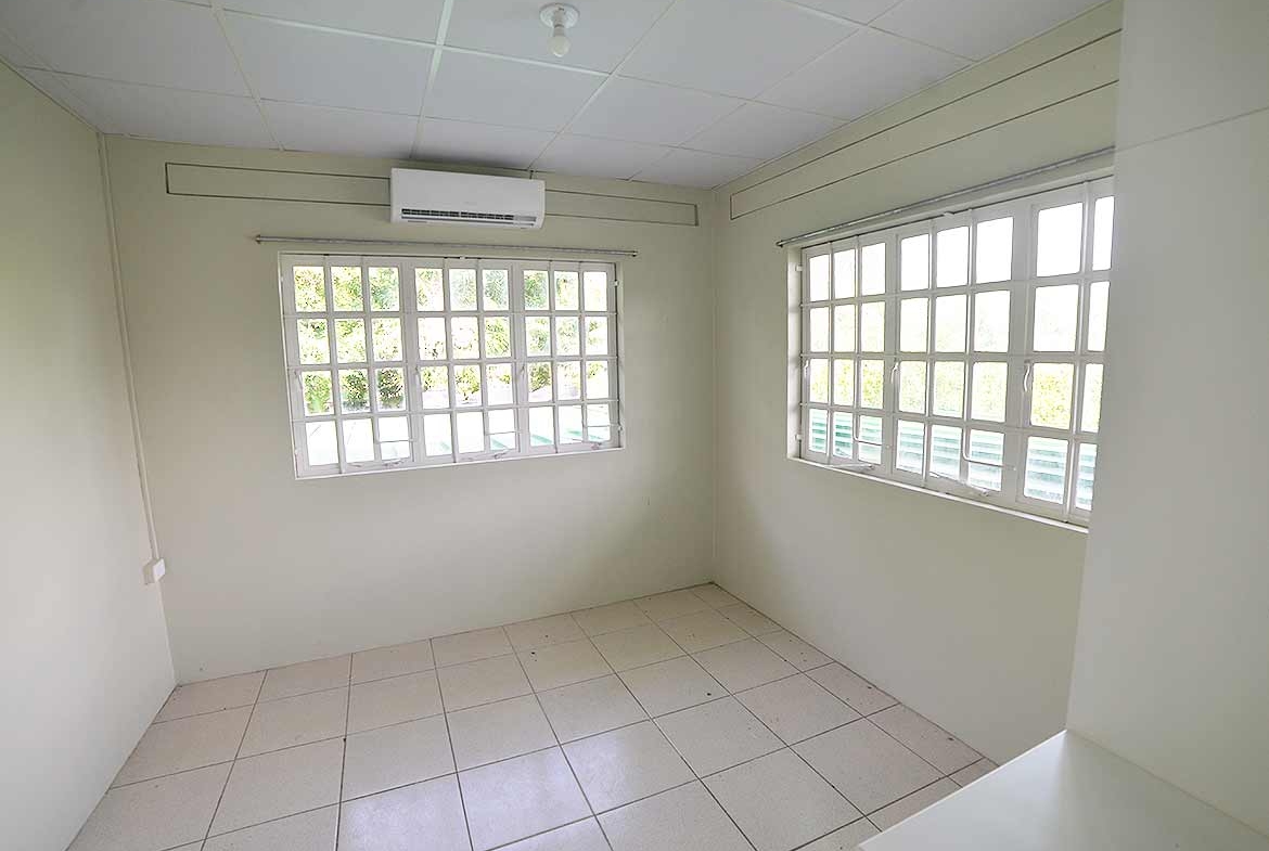 Cornerstone- Bright empty room with large windows and air conditioning unit.